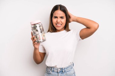 hispanic pretty woman feeling stressed, anxious or scared, with hands on head. dollar banknotes savings concept