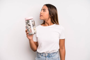 hispanic pretty woman on profile view thinking, imagining or daydreaming. dollar banknotes savings concept