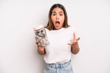 hispanic pretty woman feeling extremely shocked and surprised. dollar banknotes savings concept