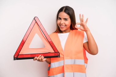 hispanic pretty woman feeling happy, showing approval with okay gesture. car accident emergency concept