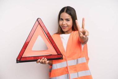 hispanic pretty woman smiling and looking happy, gesturing victory or peace. car accident emergency concept