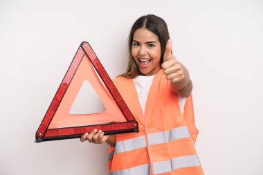 hispanic pretty woman feeling proud,smiling positively with thumbs up. car accident emergency concept