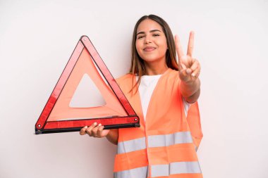 hispanic pretty woman smiling and looking friendly, showing number two. car accident emergency concept