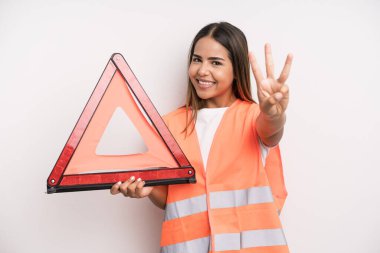 hispanic pretty woman smiling and looking friendly, showing number three. car accident emergency concept