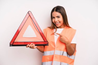 hispanic pretty woman smiling cheerfully, feeling happy and pointing to the side. car accident emergency concept