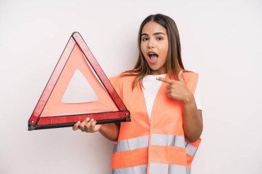 hispanic pretty woman looking excited and surprised pointing to the side. car accident emergency concept