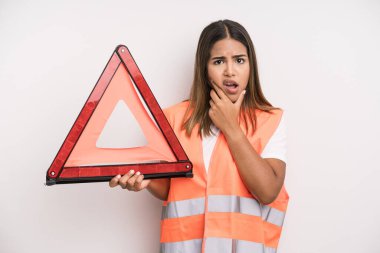 hispanic pretty woman with mouth and eyes wide open and hand on chin. car accident emergency concept