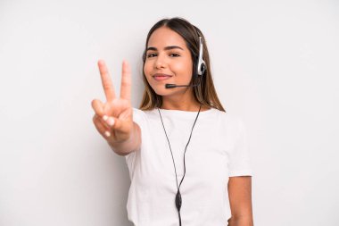 hispanic pretty woman smiling and looking friendly, showing number two. telemarketer concept