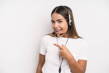 hispanic pretty woman looking excited and surprised pointing to the side. telemarketer concept