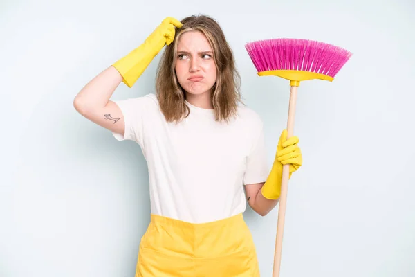 caucasian pretty woman feeling puzzled and confused, scratching head. housekeeper cleaning concept