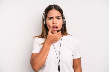 hispanic pretty woman with mouth and eyes wide open and hand on chin. telemarketer concept