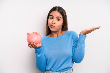 İspanyol güzel kadın şaşkın, şaşkın ve şüpheci hissediyor. Domuz kumbarası konsepti