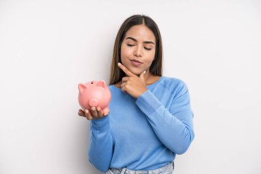 Mutlu, kendine güvenen, elleri çenesinde gülümseyen İspanyol güzel kadın. Domuz kumbarası konsepti