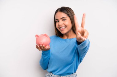 İspanyol güzel kadın gülümsüyor ve mutlu görünüyor, zafer ya da barış işareti yapıyor. Domuz kumbarası konsepti