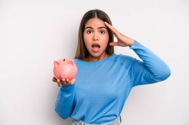 İspanyol güzel kadın mutlu, şaşkın ve şaşırmış görünüyor. Domuz kumbarası konsepti