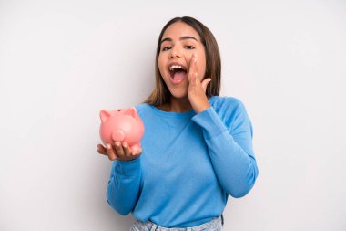 İspanyol güzel kadın kendini mutlu hissediyor, elleri ağzının kenarında bağırıyor. Domuz kumbarası konsepti