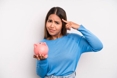 İspanyol güzel kadın kafası karışık ve şaşkın hissediyor, senin deli olduğunu gösteriyor. Domuz kumbarası konsepti