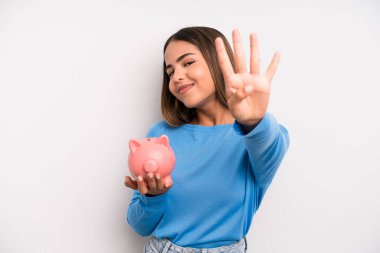 İspanyol güzel kadın gülümsüyor ve arkadaş canlısı görünüyor, dört numarayı gösteriyor. Domuz kumbarası konsepti