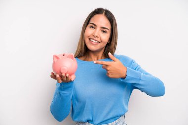 İspanyol güzel kadın neşeyle gülümsüyor, mutlu hissediyor ve bir tarafı işaret ediyor. Domuz kumbarası konsepti