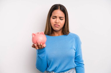 Hispanik güzel kadın üzgün, üzgün ya da kızgın hissediyor ve yana bakıyor. Domuz kumbarası konsepti