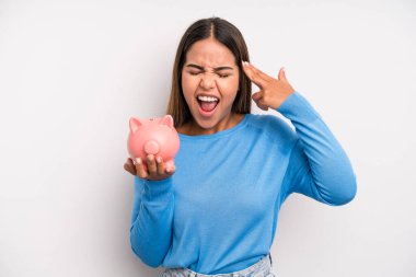 İspanyol güzel kadın mutsuz ve stresli görünüyor, intihar jesti silah işareti yapıyor. Domuz kumbarası konsepti