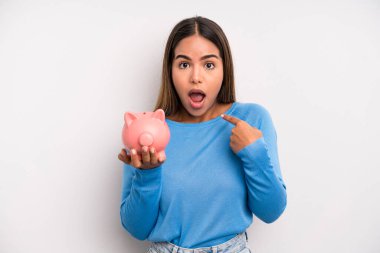 İspanyol güzel kadın şok olmuş ve ağzı açık bir şekilde kendini işaret ederek şaşırmış görünüyor. Domuz kumbarası konsepti