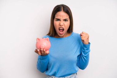 İspanyol güzel kadın sinirli bir ifadeyle agresif bir şekilde bağırıyor. Domuz kumbarası konsepti