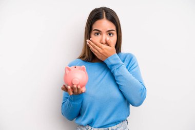 İspanyol asıllı güzel bir kadın elleri ile ağzını kapatıyor. Domuz kumbarası konsepti