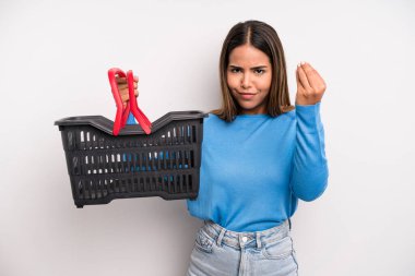 hispanic pretty woman making capice or money gesture, telling you to pay. empty supermarket basket concept