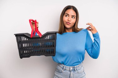 hispanic pretty woman looking arrogant, successful, positive and proud. empty supermarket basket concept