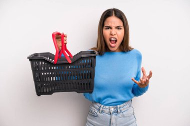 hispanic pretty woman looking angry, annoyed and frustrated. empty supermarket basket concept