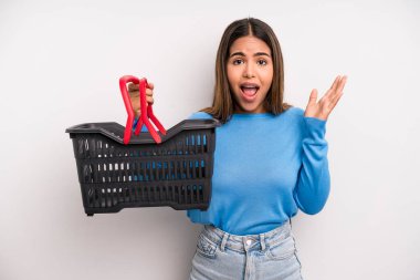 hispanic pretty woman feeling happy, surprised realizing a solution or idea. empty supermarket basket concept