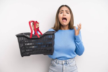 hispanic pretty woman looking desperate, frustrated and stressed. empty supermarket basket concept