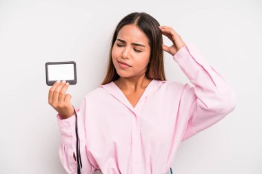 hispanic pretty woman feeling puzzled and confused, scratching head. pass id card concept