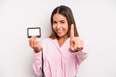hispanic pretty woman smiling proudly and confidently making number one. pass id card concept