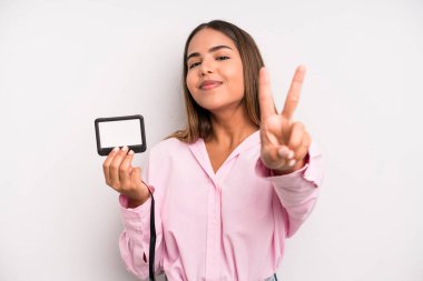 hispanic pretty woman smiling and looking friendly, showing number two. pass id card concept