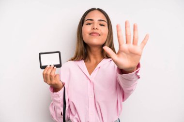 hispanic pretty woman smiling and looking friendly, showing number five. pass id card concept