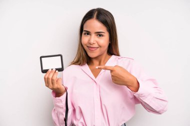 hispanic pretty woman smiling cheerfully, feeling happy and pointing to the side. pass id card concept