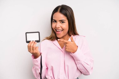hispanic pretty woman looking excited and surprised pointing to the side. pass id card concept