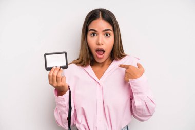 hispanic pretty woman looking shocked and surprised with mouth wide open, pointing to self. pass id card concept