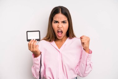 hispanic pretty woman shouting aggressively with an angry expression. pass id card concept