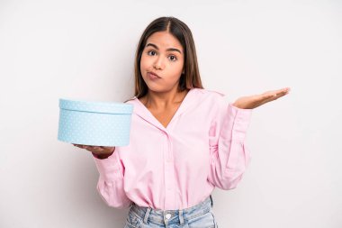 hispanic pretty woman feeling puzzled and confused and doubting. gift box concept