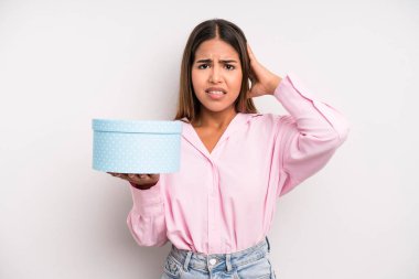 hispanic pretty woman feeling stressed, anxious or scared, with hands on head. gift box concept