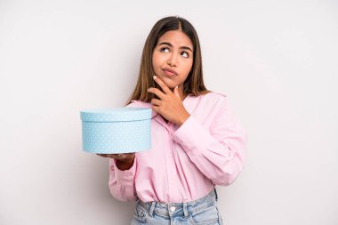 hispanic pretty woman thinking, feeling doubtful and confused. gift box concept