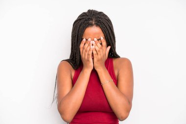 black young adult woman feeling sad, frustrated, nervous and depressed, covering face with both hands, crying