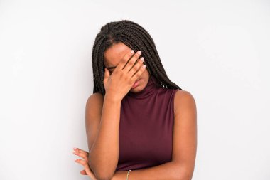 black young adult woman looking stressed, ashamed or upset, with a headache, covering face with hand