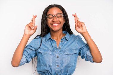 black young adult woman feeling nervous and hopeful, crossing fingers, praying and hoping for good luck