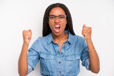 black young adult woman shouting aggressively with an angry expression or with fists clenched celebrating success