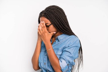 black young adult woman covering eyes with hands with a sad, frustrated look of despair, crying, side view
