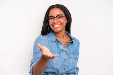 black young adult woman smiling, looking happy, confident and friendly, offering a handshake to close a deal, cooperating